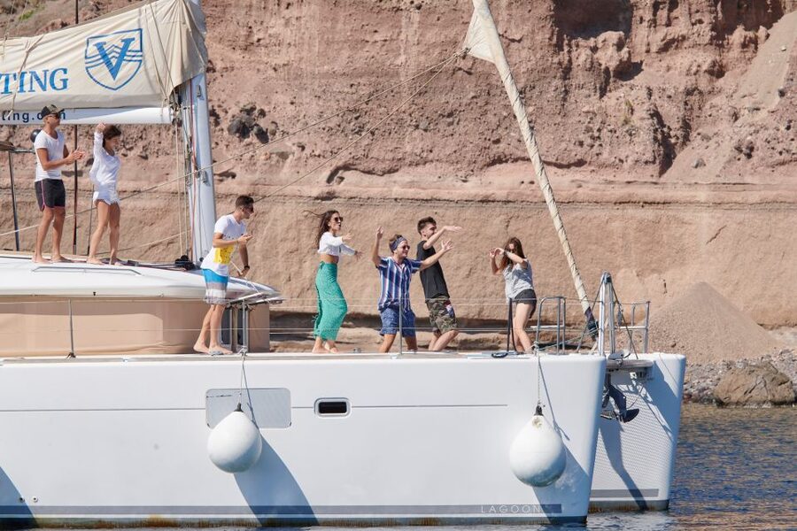 Santorini Gold Catamaran Cruise with Snorkel, BBQ & Open Bar - White Beach, Venetian lighthouse, and caldera cliff views from the water